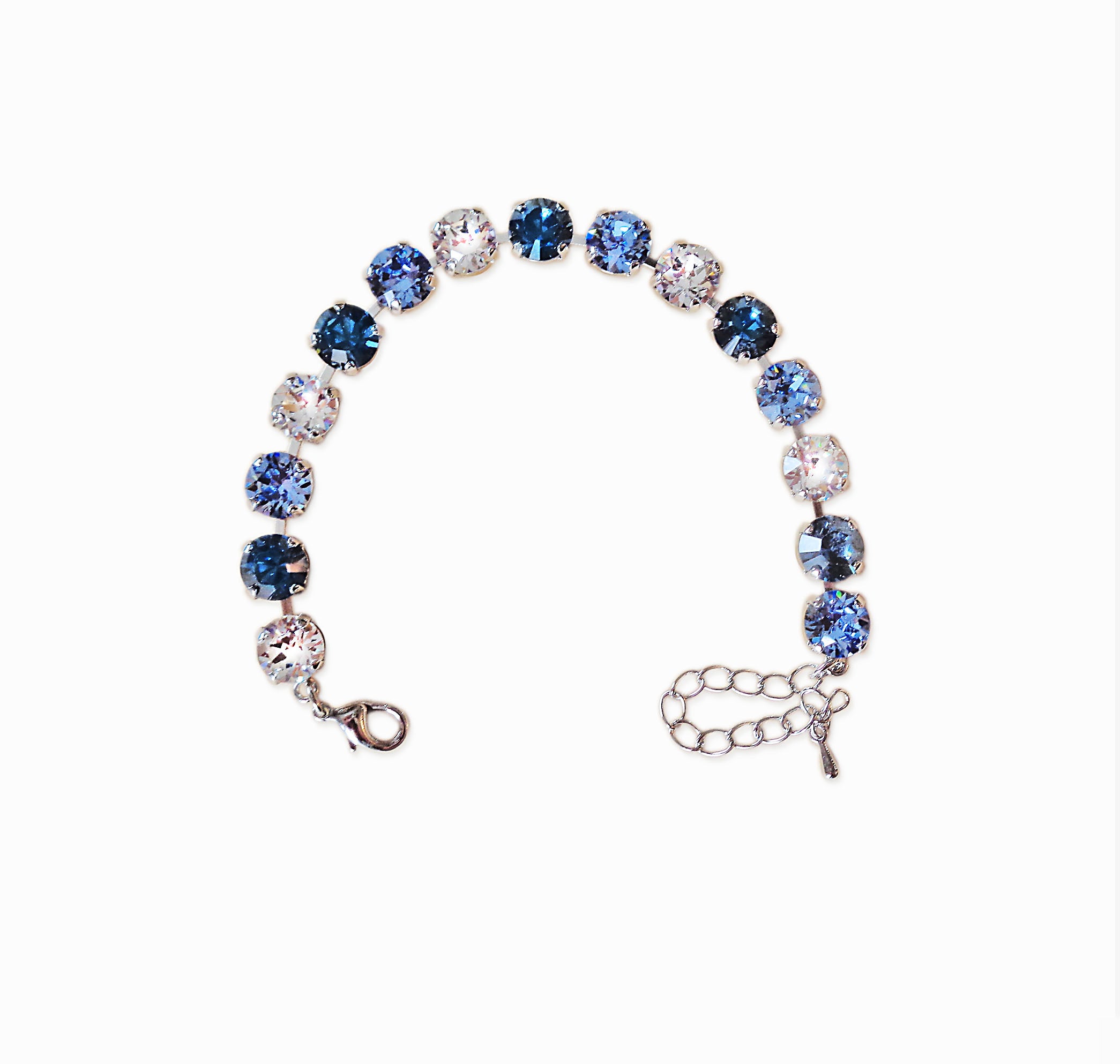 Bracelet with blue and clear gemstones on a white background.Made with genuine Austrian crystal it is a single row of crystals in colours clear crystal,light blueand dark blue.The bracelet is size medium and fits average wrist.It includes an extension chain.The metal is rhodium silver plated nickel free