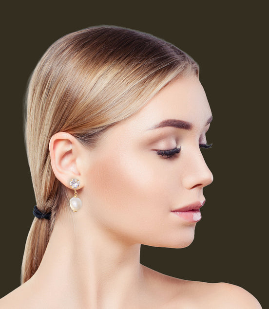 profile of a lady wearing stud and pearl drop earring in colour clear crystal and white.The studs are  gold plated with an 8mm round crystal on top and a  white freshwater pearl hanging below the stud.